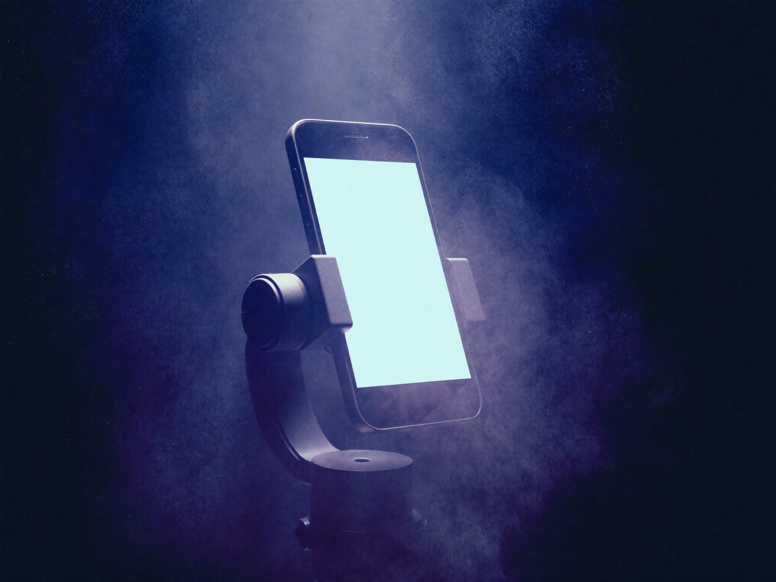 Telefon ustawiony pionowo na gimbalu, ekran świeci w fioletowej mgle